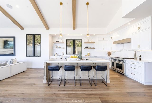 a kitchen with a stove a sink dishwasher white cabinets and couches with wooden floor