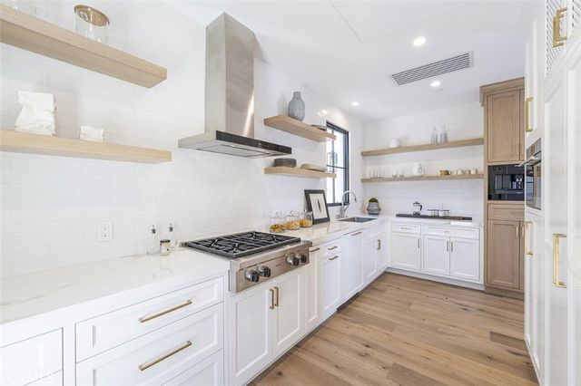 a kitchen with stainless steel appliances a sink dishwasher and stove with wooden floor