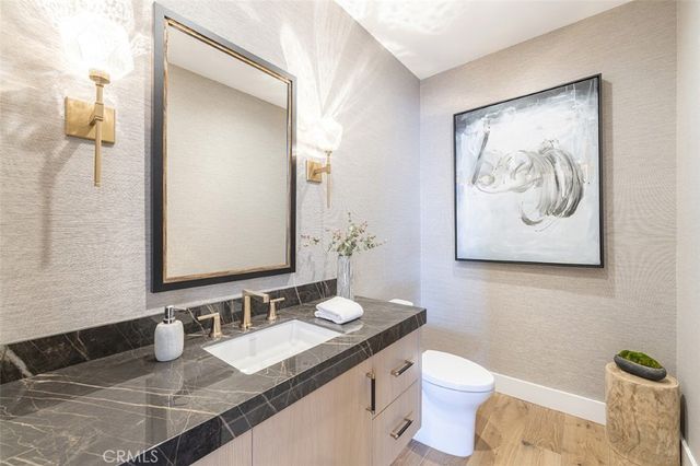 a bathroom with a granite countertop sink and a mirror with toilet