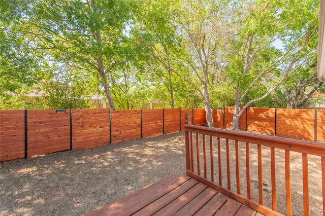 a view of a backyard with wooden fence and a large tree