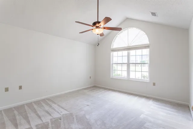 an empty room with windows and fan
