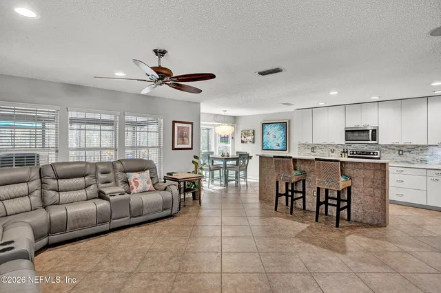 a living room with furniture a kitchen view and a refrigerator
