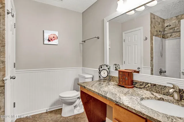 a bathroom with a granite countertop sink and a toilet
