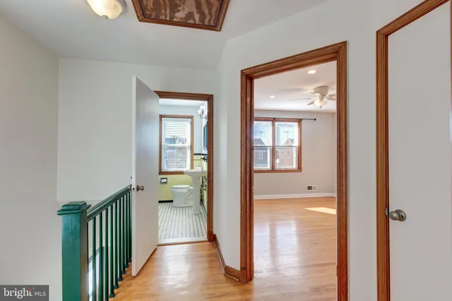 a view of a hallway with wooden floor and a bathroom