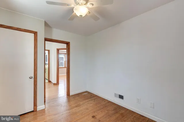 an empty room with wooden floor and chandelier fan