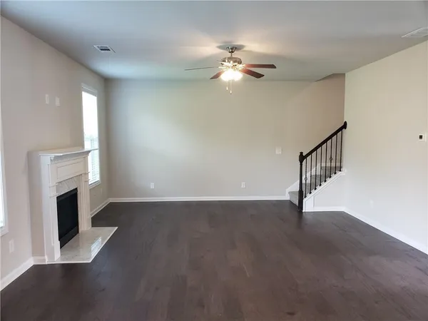 a view of an empty room with wooden floor and fireplace
