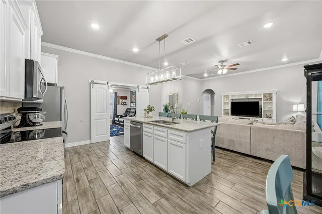 a kitchen with stainless steel appliances granite countertop a sink a stove and a wooden cabinets