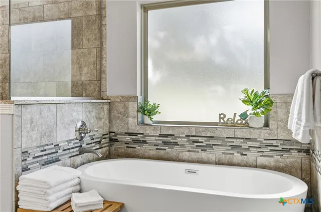 a spacious bathroom with a tub sink and mirror