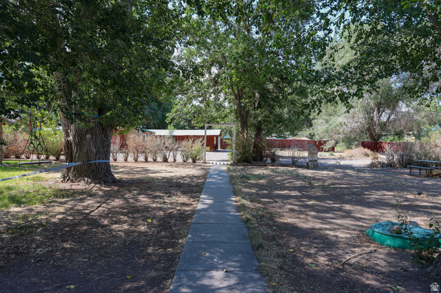 270 East 100 North Monroe, UT 84754 - Photo 45 of 65 Mature trees provide natural shade and privacy for this property, featuring a concrete pathway and a red fence line