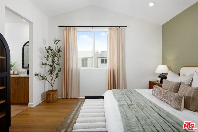 a bedroom with a large bed and a potted plant