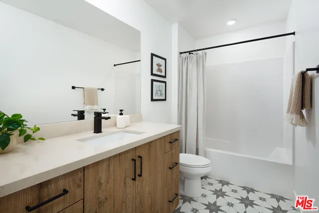 a bathroom with a granite countertop sink toilet a large mirror a shower and a bathtub