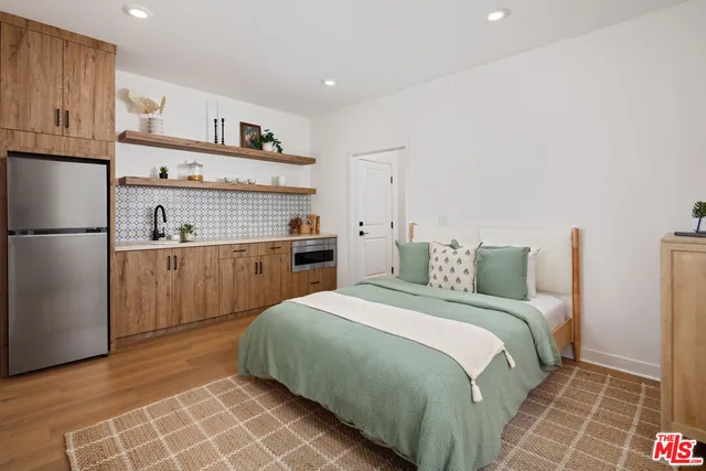 a bedroom with a bed and a refrigerator