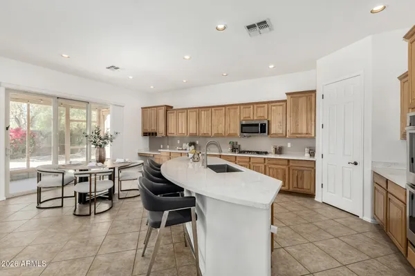 a kitchen with stainless steel appliances a table chairs microwave and refrigerator