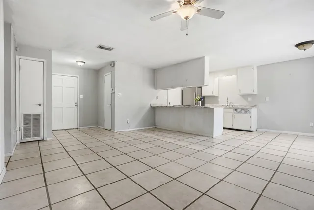 a kitchen that has a lot of white cabinets and stainless steel appliances