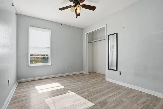 an empty room with wooden floor and a ceiling fan