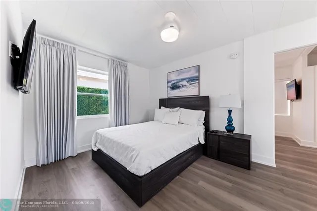 a bedroom with a bed a flat screen tv and a window