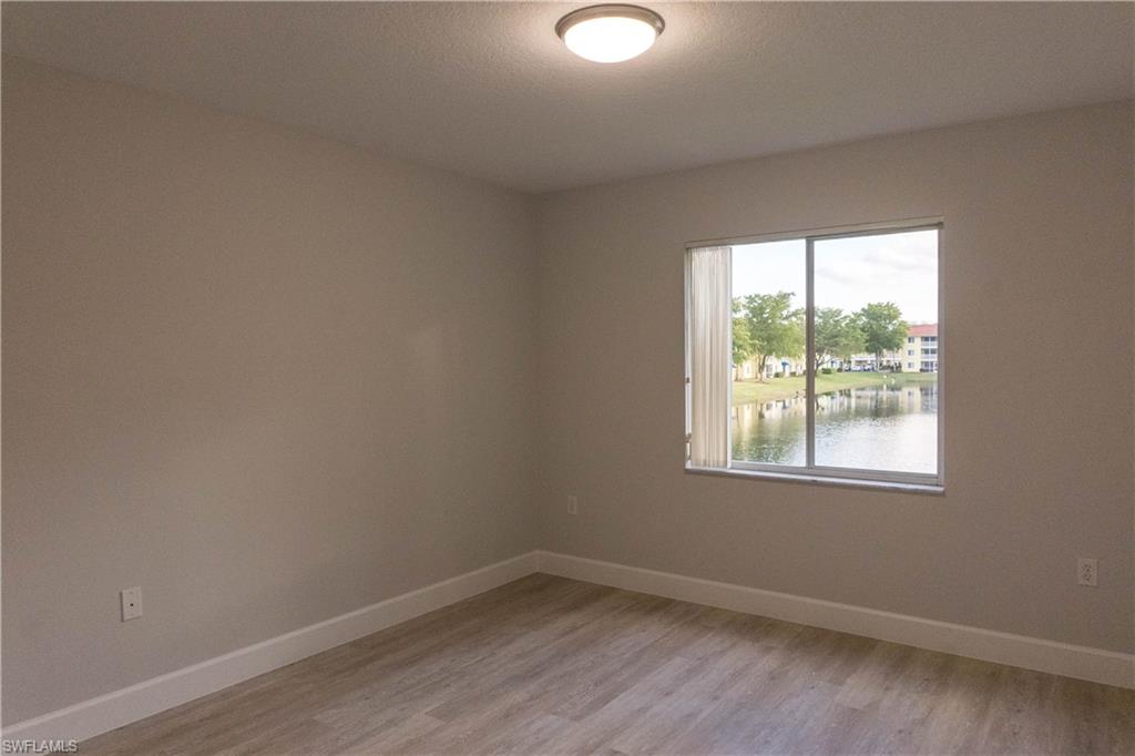8234 Key Royal Circle, Unit 523 Naples, FL 34119 - Photo 14 of 20 an empty room with wooden floor and windows