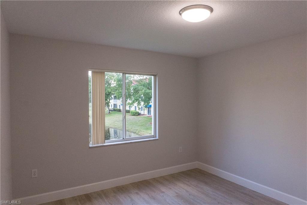 8234 Key Royal Circle, Unit 523 Naples, FL 34119 - Photo 15 of 20 an empty room with wooden floor and windows