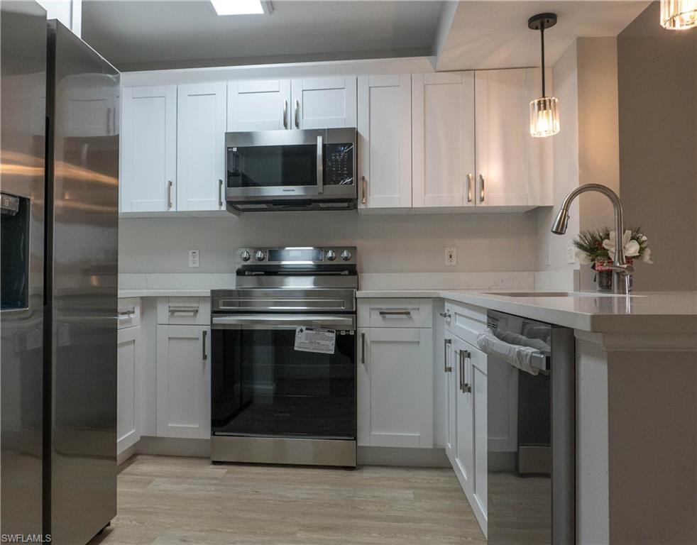 8234 Key Royal Circle, Unit 523 Naples, FL 34119 - Photo 2 of 20 a kitchen with stainless steel appliances granite countertop a stove a microwave and a refrigerator