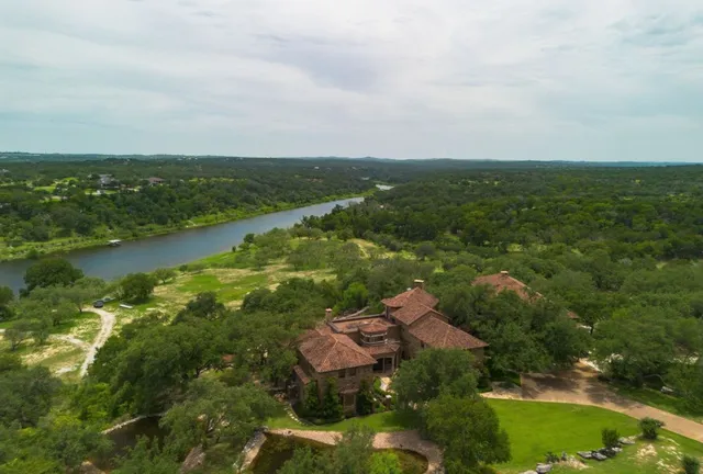 an aerial view of residential houses with outdoor space and trees