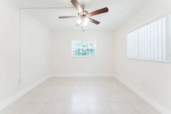 an empty room with windows and fan