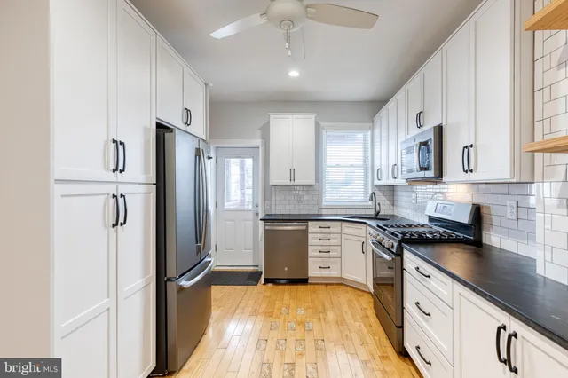 a kitchen with granite countertop cabinets stainless steel appliances and a wooden floor
