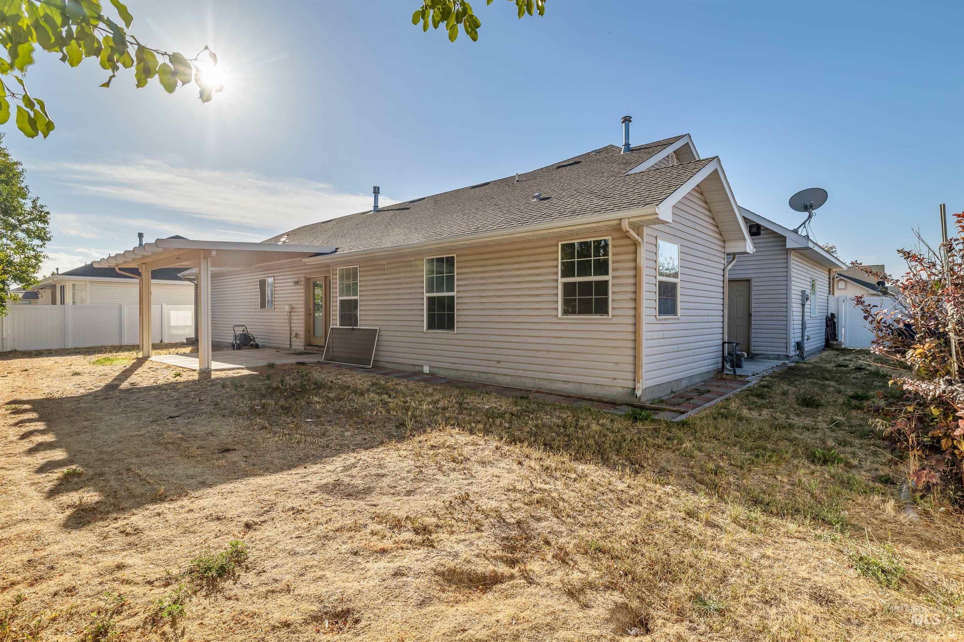 2509 Cedar Ridge Road Twin Falls, ID 83301 - Photo 26 of 36 Exterior siding with multiple windows, covered patio, rear entry door, and a partially fenced yard
