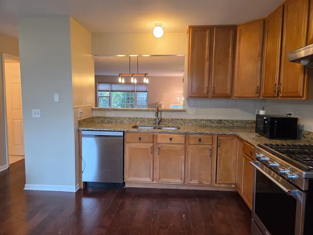 a kitchen with stainless steel appliances granite countertop a sink a stove a refrigerator and cabinets