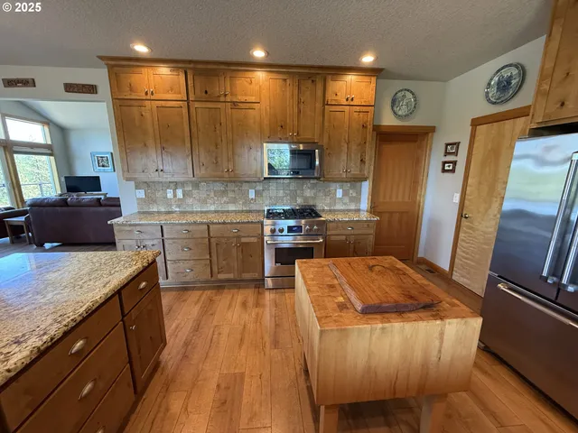 a large kitchen with stainless steel appliances kitchen island granite countertop wooden cabinets and a granite counter tops