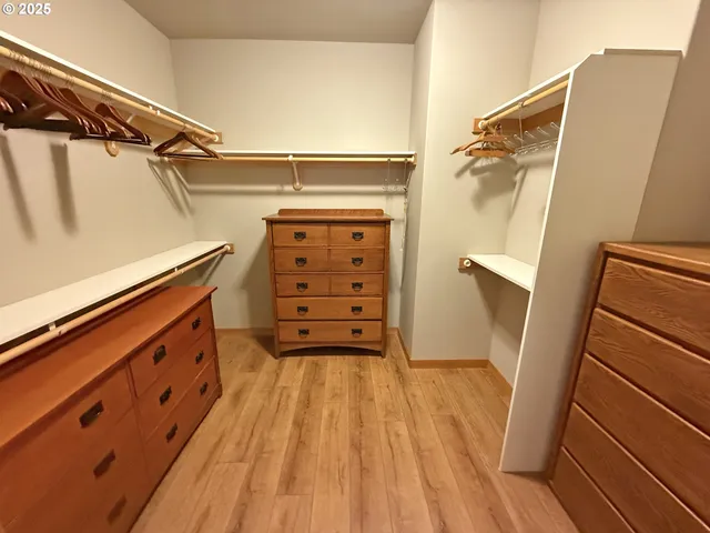 a view of walk in closet with clothes and wooden floor