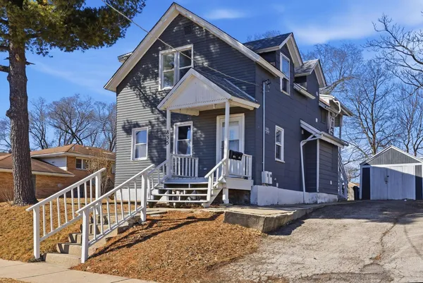 a front view of a house with wooden stairs and a bench