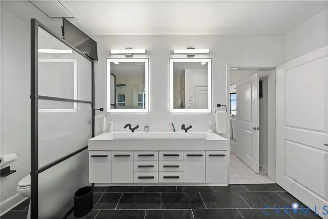 a bathroom with a sink a toilet a mirror and shower