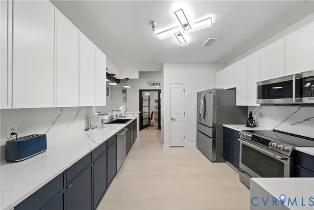 a kitchen with stainless steel appliances granite countertop a dining table chairs and a refrigerator
