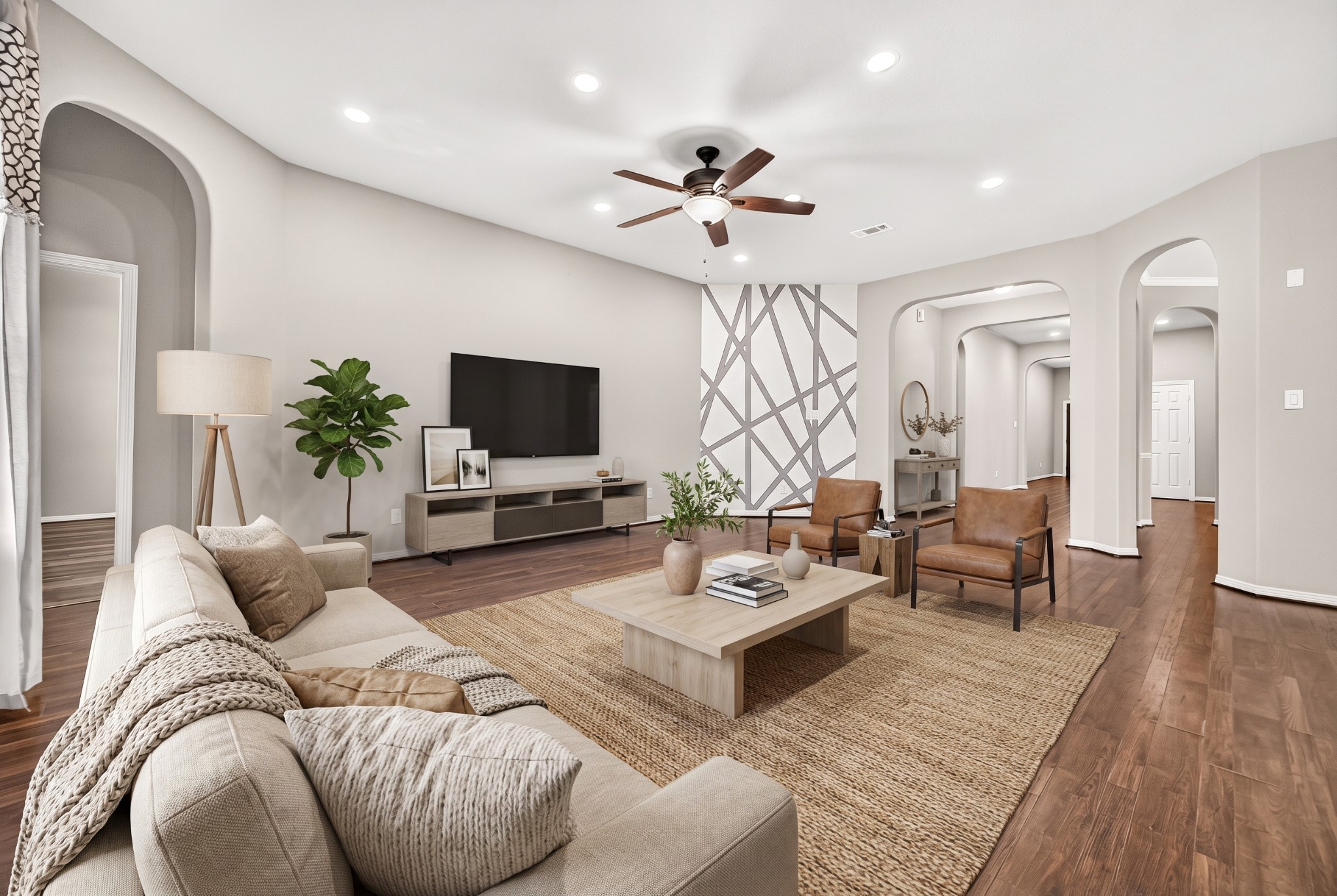 Virtually staged living room with ceiling fan, arched niche, wood-look flooring and abundant natural light.