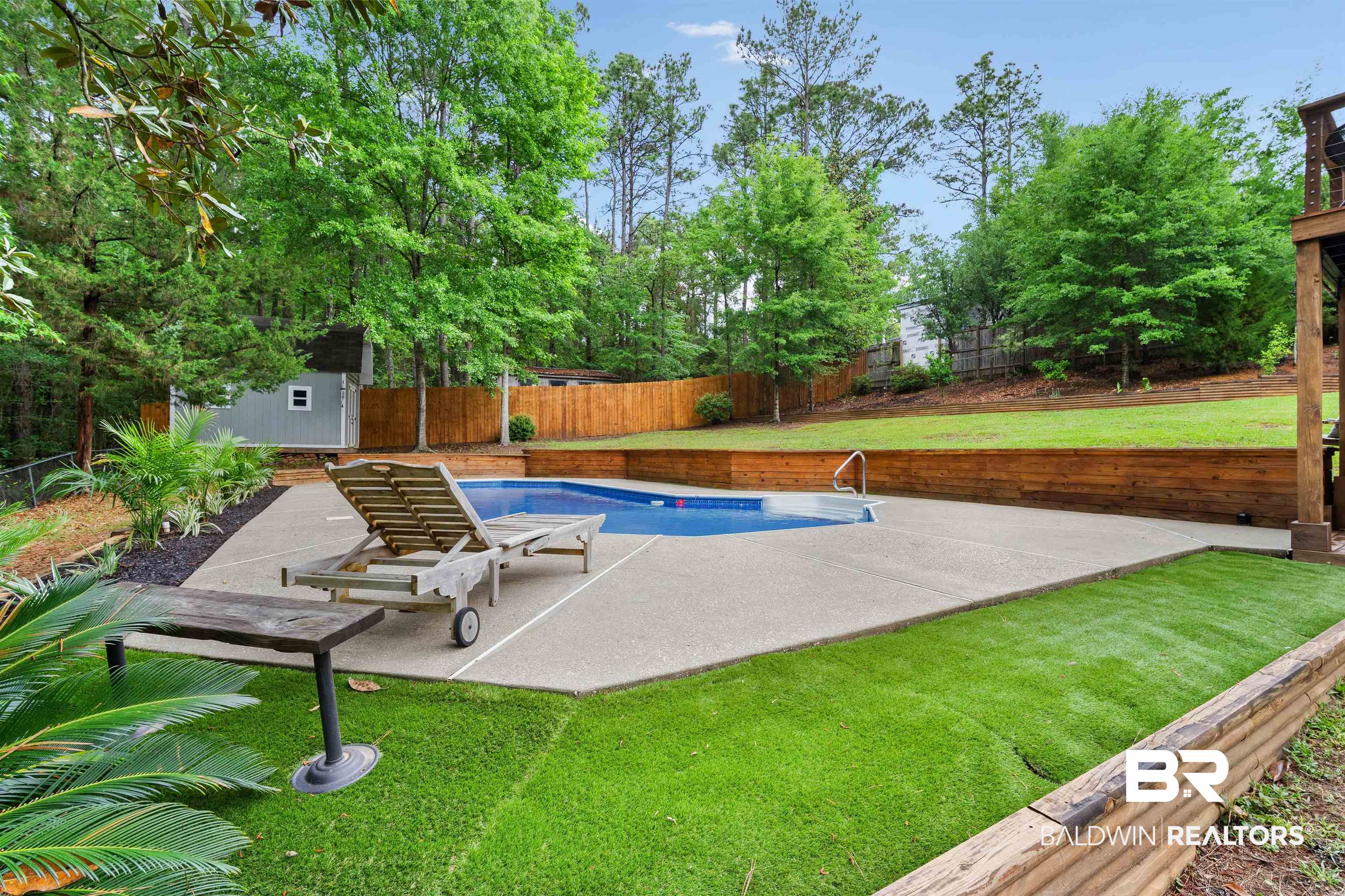 71 Caisson Trace Daphne, AL 36527 - Photo 28 of 36 Backyard oasis featuring an in-ground pool with concrete surround, artificial turf, and a wooden retaining wall
