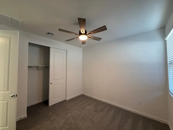 an empty room with closet and a ceiling fan