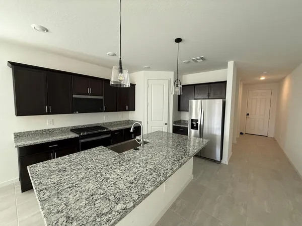 a kitchen with stainless steel appliances kitchen island granite countertop a refrigerator and a stove top oven