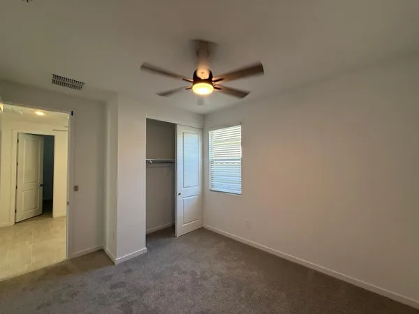 an empty room with closet and a ceiling fan