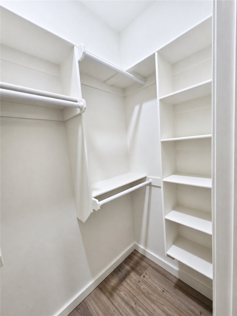 331 Channel Circle Russellville, AR 72802 - Photo 18 of 29 Walk-in closet featuring built-in shelving, multiple hanging rods, and wood-finish flooring