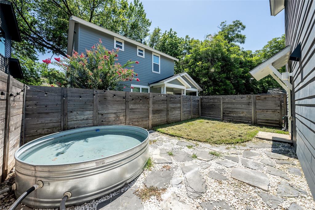 2821 Castro Street, Unit 1 Austin, TX 78702 - Photo 2 of 21 Private outdoor space featuring a galvanized stock tank, stone paver patio, partial lawn area, and wood privacy fencing