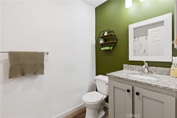 a bathroom with a granite countertop toilet sink and mirror