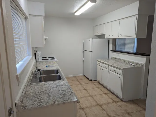 a kitchen with white cabinets and appliances