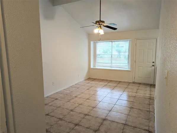 a view of an empty room and chandelier fan