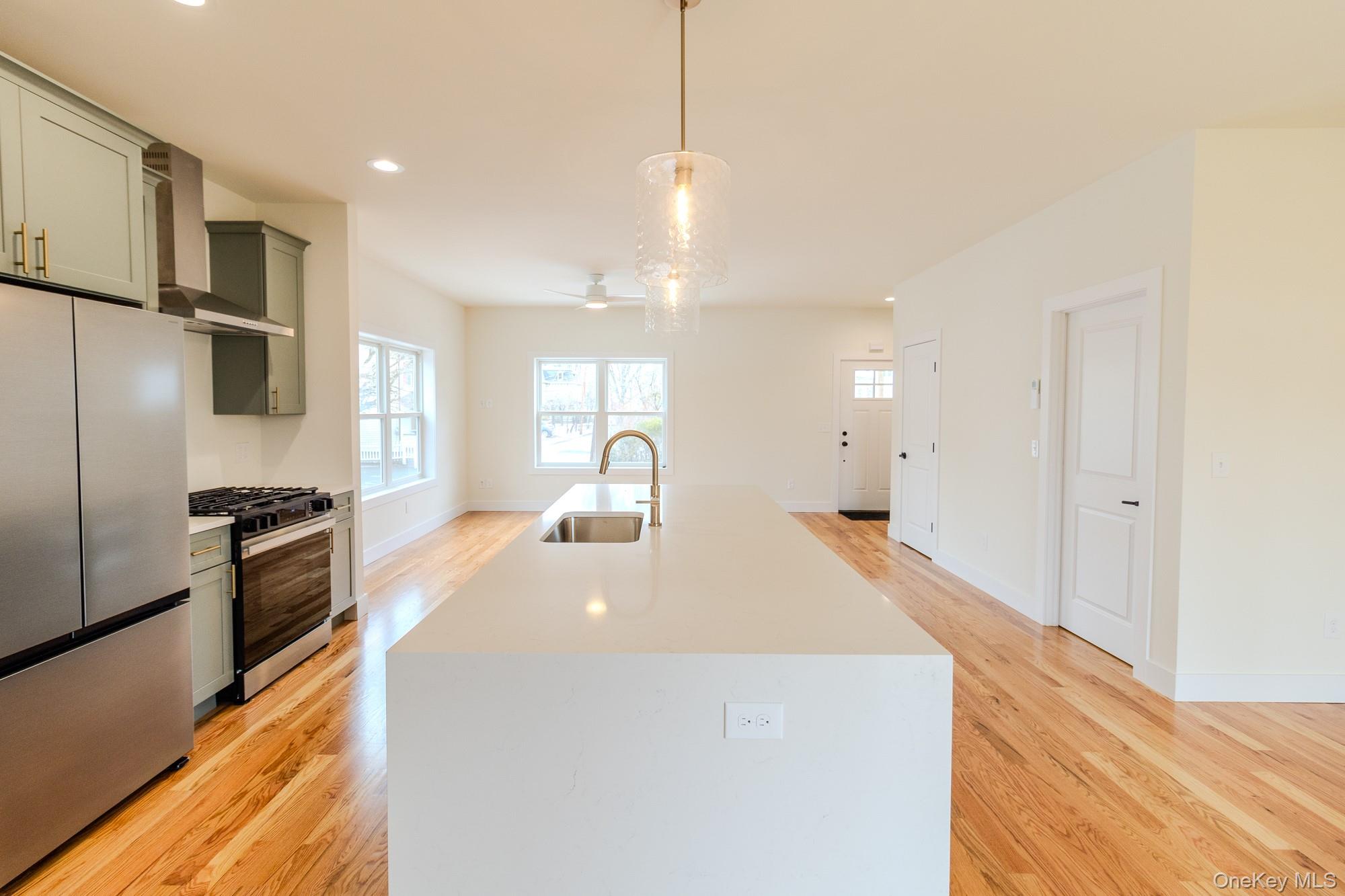 1 Ridge Avenue Port Jervis, NY 12771 - Photo 7 of 31 a large white kitchen with kitchen island a stove a sink a refrigerator and white cabinets with wooden floor