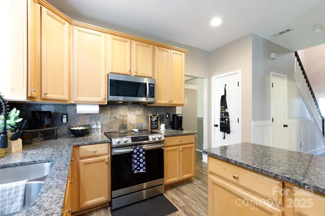 a kitchen with stainless steel appliances granite countertop a stove a sink and a microwave