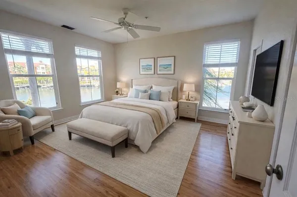 a bedroom with a bed wooden floor and windows