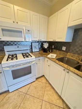 a kitchen with granite countertop white cabinets and white appliances