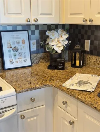 a kitchen with granite countertop white cabinets and white appliances