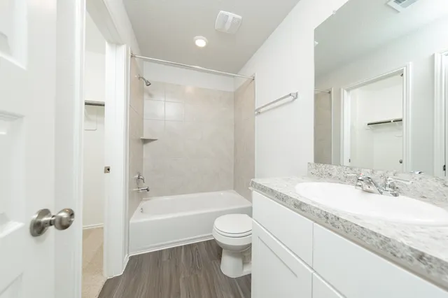 a bathroom with a granite countertop toilet a sink and a bathtub