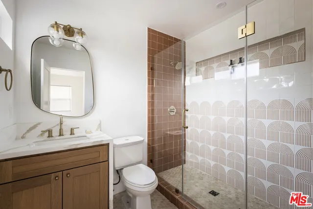 a bathroom with a toilet sink vanity granite and shower